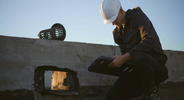a contractor is taking notes on a tablet while performing a commercial roof inspection on a flat roof in Tucson